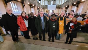 Dr.Wennemar Schweer (Pfr.i.R., Rheda-Wiedenbrück), Maxie Kordes (Ökumene-Beauftragte des Kirchenkreises Gütersloh), Yoram Karusya (Vereinte Evangelische Mission, VEM, Regionaler Dienst), Frank Schneider (Superintendent Kirchenkreis Gütersloh), Dr. Benson Boganza (Bischof), Stefan Salzmann (Vesperkirche und Pfarrer ev. Gemeinde Gütersloh) und Pastorin Deogratias Aberatha Kokuberwa (Pfarrerin Karagwe Diözese) treffen sich in der Gütersloher Vesperkirche.		Foto: Vesperkirche/Ludger Osterkamp  