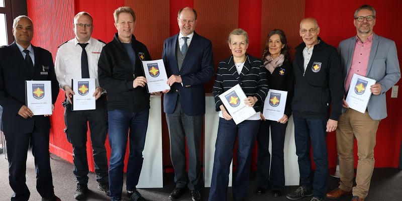 Johannes Schütze (Kreispolizeibehörde Warendorf Direktion Gefahrenabwehr/Einsatz, v. l.), Nils Recker (stv. Leiter der Kreisleitstelle), Martin Remke (Koordinator für die Notfallseelsorge im Kreis Warendorf), Landrat Dr. Olaf Gericke, Ordnungsdezernentin Petra Schreier, Petra Huß (Notfallseelsorgerin), Martin Kofoth (Feuerwehrseelsorger) und Michael Frerich (Amtsleiter Bevölkerungsschutz) bei der Übergabe des Jahresberichts. Foto: Kreis Warendorf